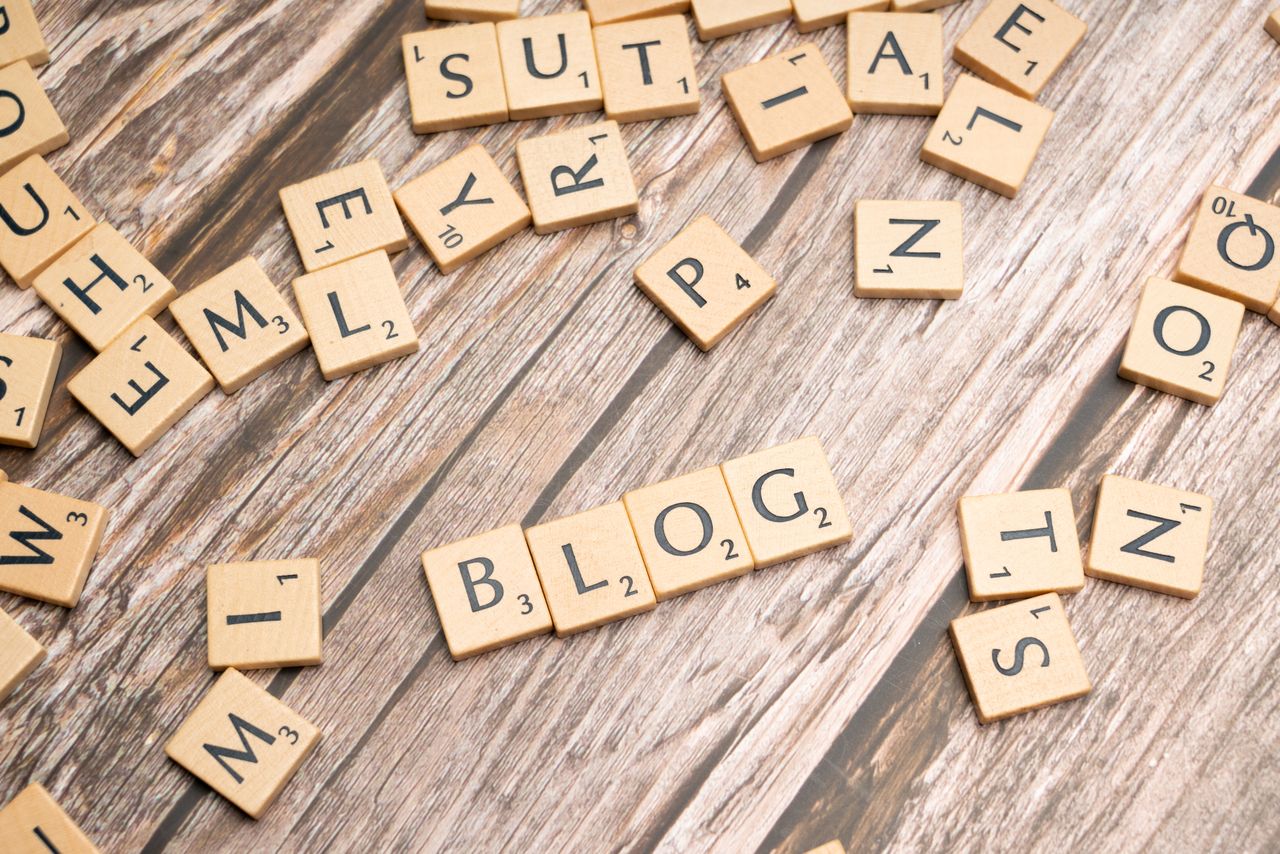 Scattered wooden letter tiles spelling 'Blog' on a rustic wood background.