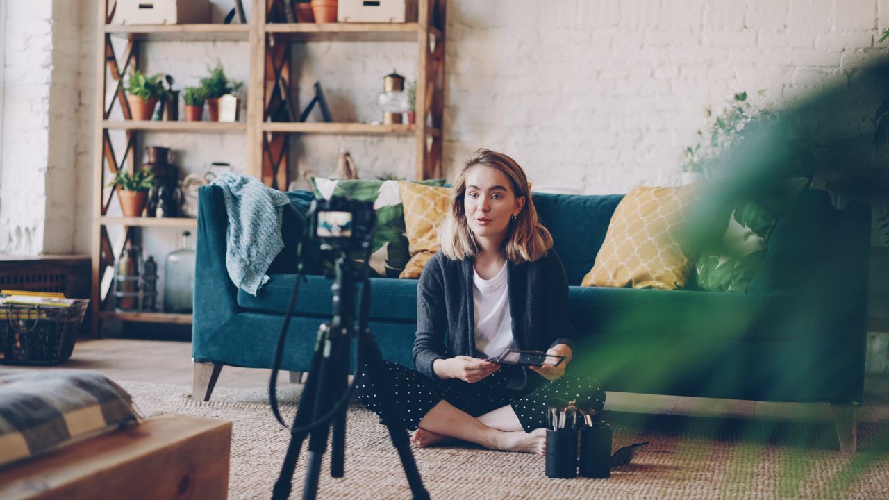 Home Woman filming vlog at home with camera setup, surrounded by plants and cozy decor.